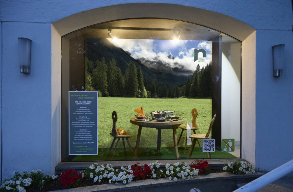Sauber Bleiben campaign poster in an illuminated shop window at night, Kleinwalsertal, photograph by Mathias Kessler