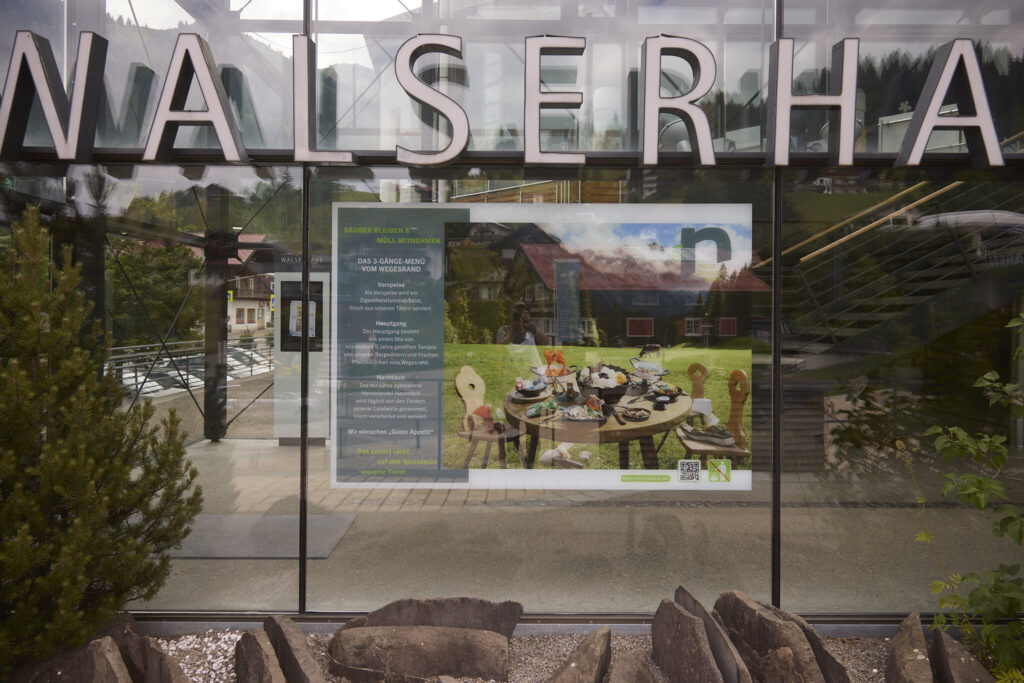 Campaign poster reflected in the glass facade of the Walserhaus, Hirschegg Kleinwalsertal
