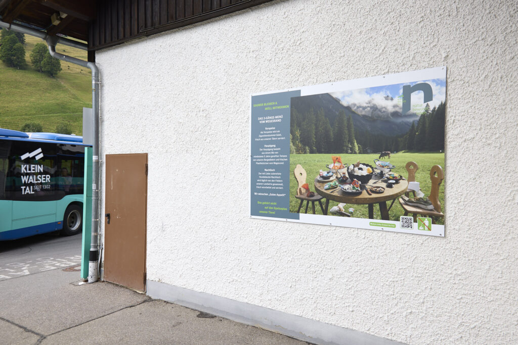 Sauber Bleiben campaign billboard on a house wall in the Kleinwalsertal with local bus passing