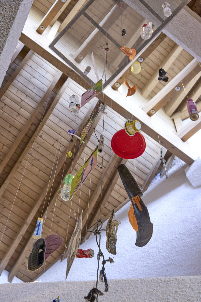 Suspended litter objects of the trash mobile under the timber roof of the Walserhaus, Kleinwalsertal