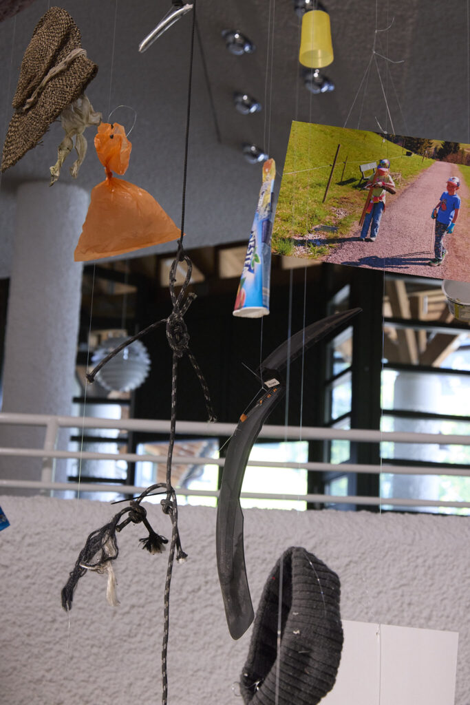 Detail of the trash mobile installation with suspended litter and landscape photographs, Walserhaus Hirschegg, Kleinwalsertal